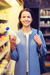 Image showing happy woman holding milk bottle in market