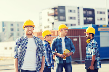 Image showing group of smiling builders in hardhats outdoors