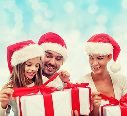 Image showing happy family in santa hats sitting with gift boxes