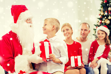 Image showing smiling family with santa claus and gifts at home