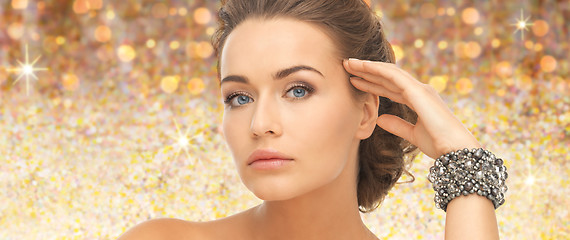 Image showing beautiful woman with bracelet over golden lights