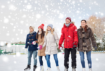 Image showing happy friends ice skating on rink outdoors