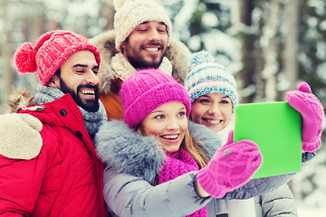 Image showing smiling friends with tablet pc in winter forest