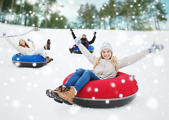 Image showing group of happy friends sliding down on snow tubes