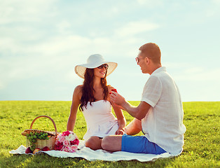 Image showing smiling couple with small red gift box on picnic