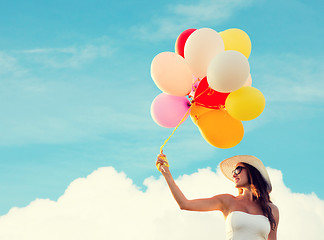 Image showing smiling young woman in sunglasses with balloons