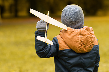 Image showing happy little boy playing with toy plane outdoors