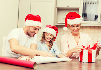 Image showing smiling family in santa helper hats with gift box