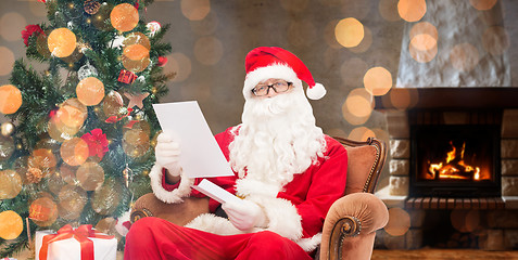 Image showing santa claus reading letter in armchair at home