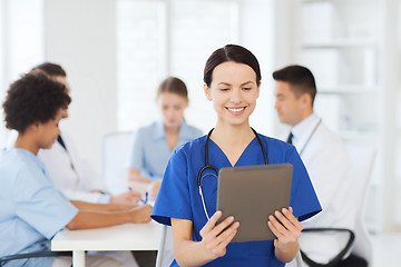 Image showing happy doctor with tablet pc over team at clinic