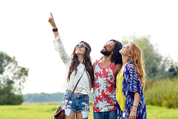 Image showing happy hippie friends pointing finger outdoors