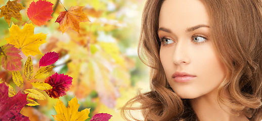 Image showing beautiful young woman face over autumn leaves