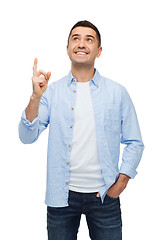 Image showing smiling man pointing finger up