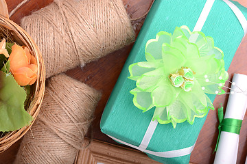 Image showing green christmas gift box, white paper with bow on wooden table.