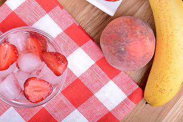 Image showing A slice of red strawberry on glass plate with bananas and peach, health food concept