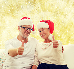 Image showing happy senior couple in santa helper hats