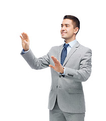 Image showing happy businessman in suit touching something