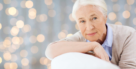 Image showing happy senior woman resting on sofa over lights