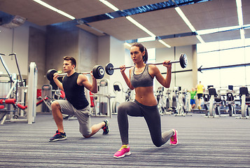 Image showing young man and woman training with barbell in gym