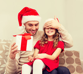 Image showing smiling father surprises daughter with gift box