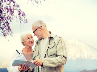 Image showing happy senior couple with travel map over mountains