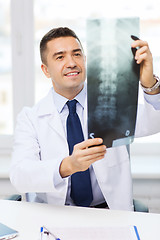 Image showing smiling male doctor in white coat looking at x-ray