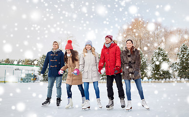 Image showing happy friends ice skating on rink outdoors