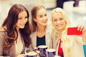 Image showing smiling young women with cups and smartphone