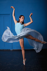 Image showing young modern ballet dancer posing on blue background