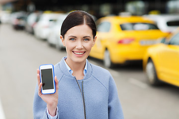 Image showing smiling woman showing smartphone over taxi in city