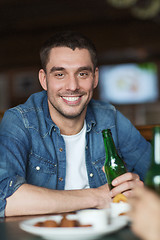 Image showing happy young man drinking beer at bar or pub