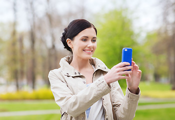 Image showing smiling woman taking picture with smartphone