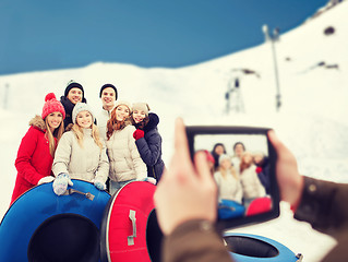 Image showing smiling friends with snow tubes and tablet pc