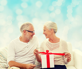 Image showing happy senior couple with gift box at home