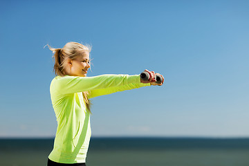 Image showing sporty woman with light dumbbells outdoors