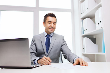 Image showing smiling businessman with laptop and papers