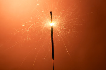 Image showing Burning sparkler on an orange background