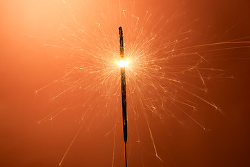 Image showing Burning sparkler on an orange background