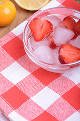 Image showing A slice of red strawberry on glass plate with lemon and mandarin in party theme background