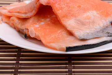 Image showing Raw salmon fish steaks with fresh herbs on white plate