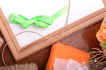 Image showing Christmas gift box and empty wooden frame on wooden table