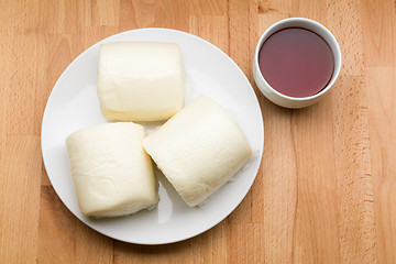 Image showing Steamed bun hold with glass of tea