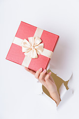 Image showing Hand break through paper with red gift box