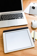 Image showing Busy working desk with blank screen of tablet for advertising