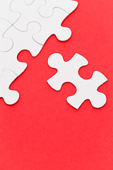 Image showing Incomplete white puzzle with red color background