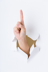 Image showing Woman hand breaking through paper wall with finger point up