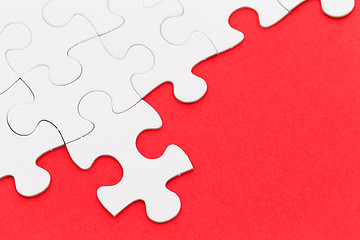 Image showing Incomplete white puzzle with red color background