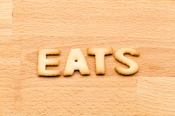 Image showing Word eats biscuit over the wooden background