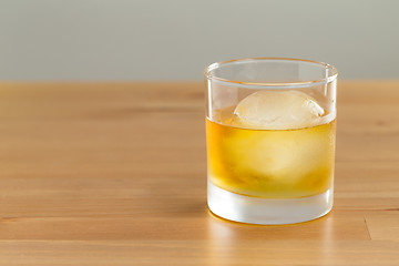 Image showing Whiskey drink on wood with ice cube