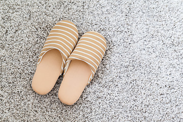Image showing Soft brown color slippers on carpet 